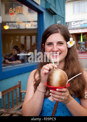 Une jolie fille brune jouit d'un Hawaiian shave ice (shaved ice) de la glace dans le rasage scandinaves Kailua-Kona, Hawaii. Banque D'Images