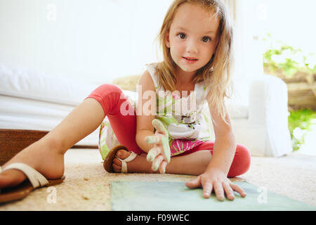 Portrait de la belle petite lycéenne en coloriant un dessin. Girl's hands peints avec la couleur de craie verte looking at camera. Banque D'Images