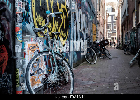 Vélo dans une ruelle à Amsterdam, sur un mur de graffiti urbain Banque D'Images