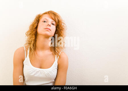 Redhaired young woman leaning on wall intérieur Banque D'Images