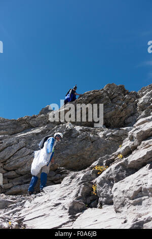 Les cavaliers sont de BASE Wingsuit descendre sur une corde à la plate-forme et préparer leur sortie wingsuit et passe de la falaise. Banque D'Images