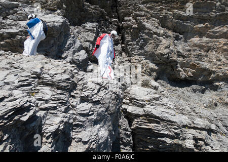 Les cavaliers DE BASE Wingsuit s'apprêtent à sauter d'une falaise et contrôle de l'altitude par vers le bas et réglage de ses ailes. Banque D'Images