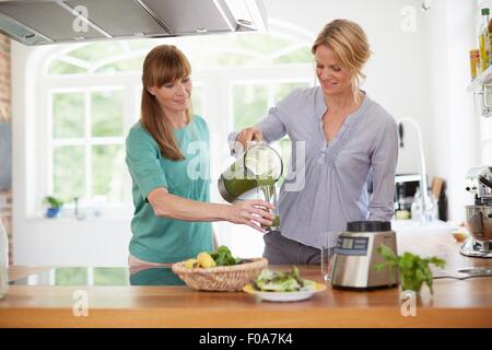 Les femmes végétaliennes vert potable dans la cuisine smoothie Banque D'Images