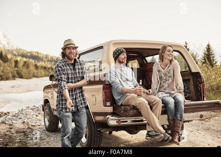 Trois personnes assises à l'arrière du pick-up smiling Banque D'Images