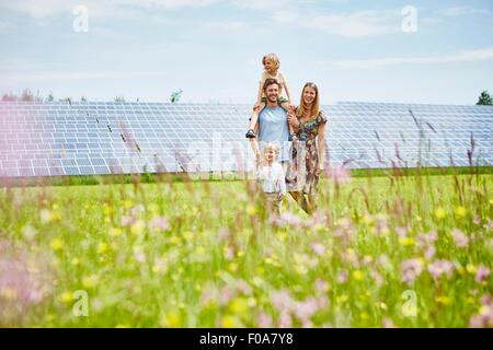 Jeune famille, marche à travers champ en regard de la ferme solaire Banque D'Images