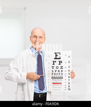 Opticien à maturité la tenue d'un tableau et en pointant sur elle avec un bâton en bois dans un hôpital Banque D'Images