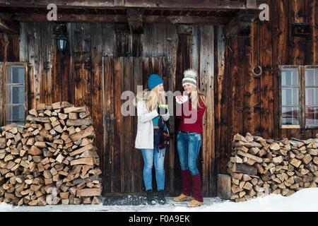 Deux jeunes femmes friends chatting extérieur chalet en bois Banque D'Images