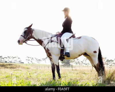 Portrait of teenage girl riding horse in field Banque D'Images