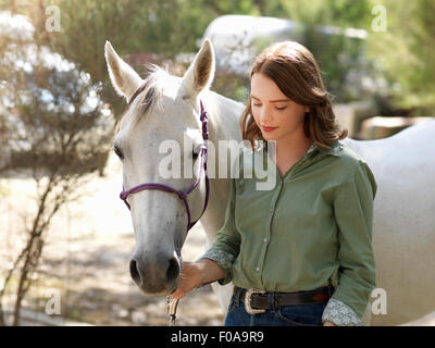 Portrait of teenage girl with grey horse on farm Banque D'Images