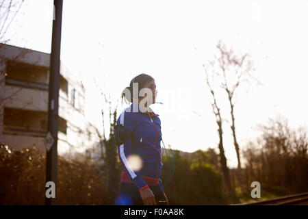 Femelle adulte runner dans park listening to music on headphones Banque D'Images