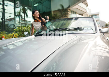 Young woman getting en voiture décapotable Banque D'Images