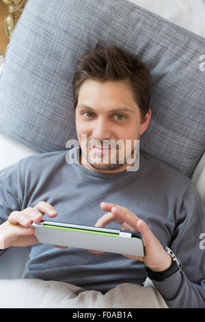 Man using digital tablet on bed Banque D'Images