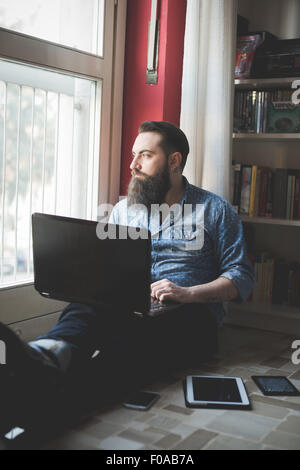 Jeune homme barbu à l'aide de l'ordinateur portable sur marbre Banque D'Images