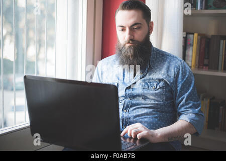 Jeune homme barbu à l'aide de l'ordinateur portable sur marbre Banque D'Images