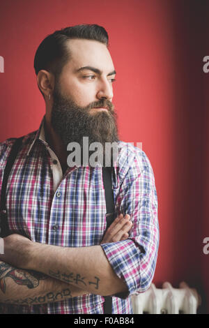 Portrait de jeune homme barbu, fond rouge Banque D'Images