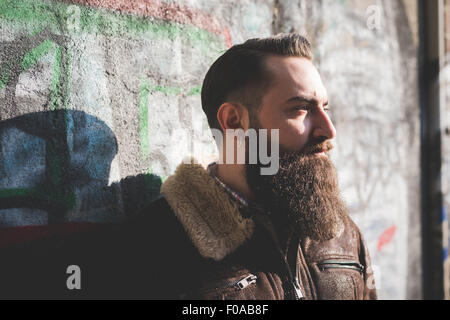 Jeune homme barbu par le graffiti wall Banque D'Images