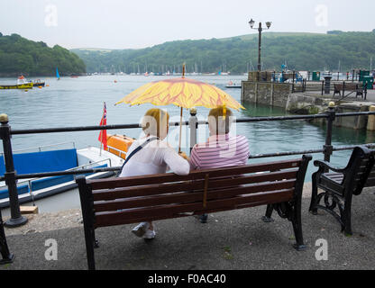 L'homme et de la femme sous la pluie parapluie en donnant à l'estuaire de Fowey, Cornwall, England, UK Banque D'Images