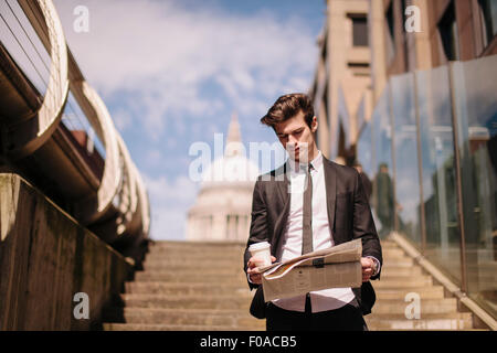 Young Woman Reading newspaper walking down escalier ville Banque D'Images