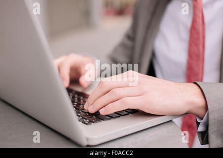 Mains de ville jeune businessman typing on laptop at sidewalk cafe Banque D'Images