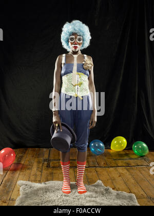 Portrait of young woman wearing clown face paint et perruque bleu sur scène Banque D'Images