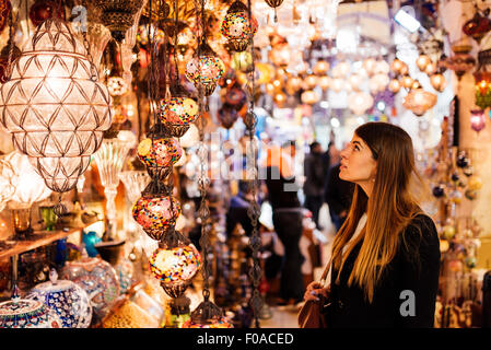 Jeune femme à la recherche de lumières sur market stall, Istanbul, Turquie Banque D'Images