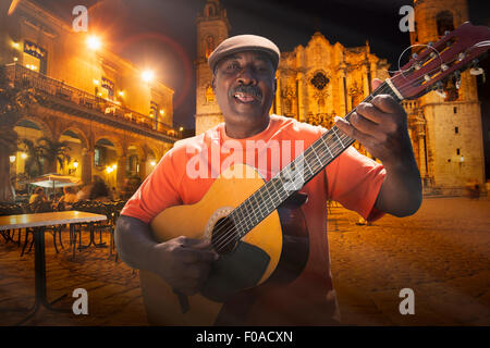 Senior man playing acoustic guitar sur la Plaza de la cathédrale de nuit, La Havane, Cuba Banque D'Images