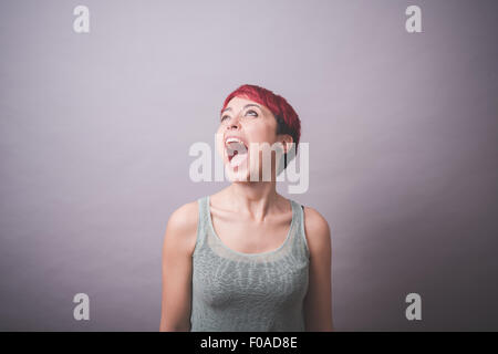 Studio portrait de jeune femme avec de courts cheveux roses criant Banque D'Images