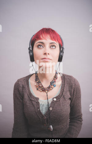 Studio portrait de jeune femme avec de courts cheveux roses portant des écouteurs Banque D'Images
