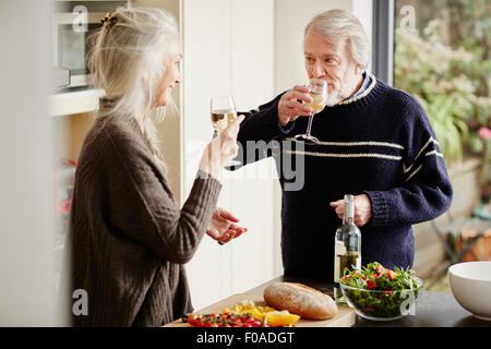 Senior couple drinking wine in kitchen Banque D'Images