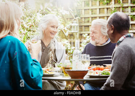 Senior friends eating meal in garden Banque D'Images