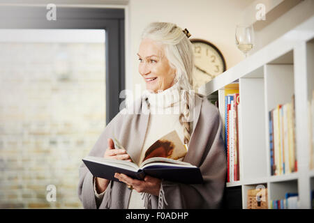 Senior woman reading book at home Banque D'Images