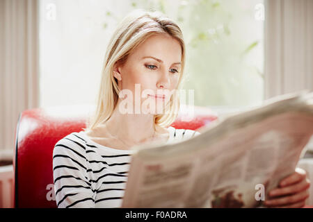 Mid adult woman reading newspaper Banque D'Images