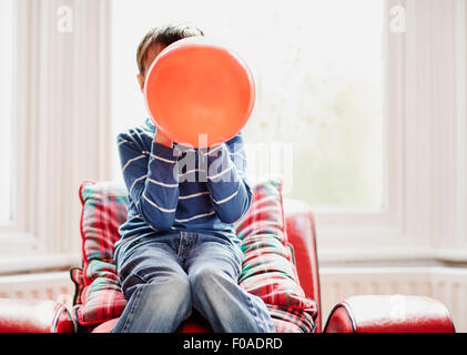 Young boy holding balloon en face de visage Banque D'Images