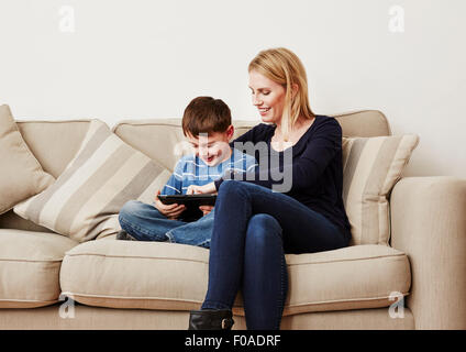 Young boy using digital tablet with mother Banque D'Images