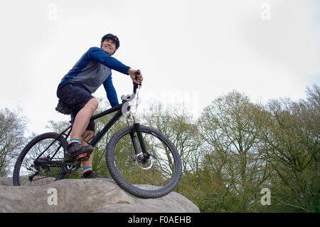 Low angle view of male mountain biker à partir de rock formation Banque D'Images