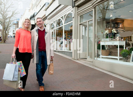 Couple carrying shopping bags sur village street Banque D'Images