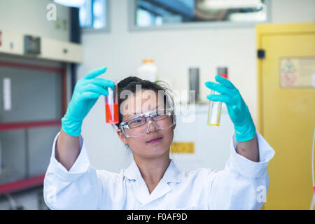 Young female scientist comparant deux échantillons in lab Banque D'Images