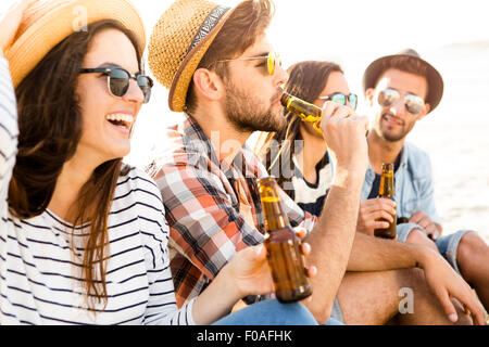 Les amis de s'amuser ensemble à la plage et de boire une bière froide Banque D'Images