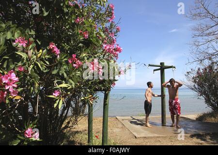 Les hommes prenant une douche dans Icmeler beach, Parc National de la péninsule de Dilek, Kusadasi, Turquie Banque D'Images