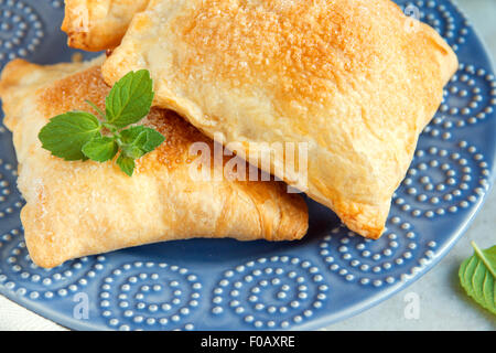 La pâte feuilletée avec du sucre et de la menthe close up sur plaque bleue Banque D'Images