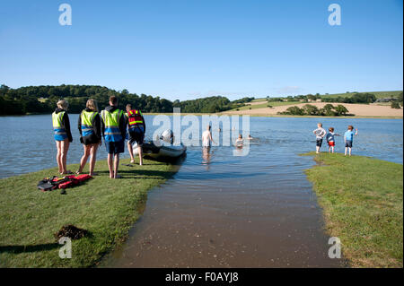 Les nageurs braver les eaux fraîches de l'estuaire à marée haute au Port Eliot Festival à Cornwall Banque D'Images