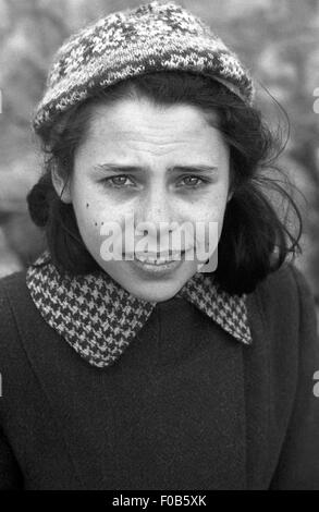 Une jeune fille portant un manteau et woolly hat smiling at the camera. Banque D'Images