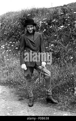 Une jeune fille en vêtements, manteau, chapeau melon et jodhpurs tenant un petit fouet. Banque D'Images