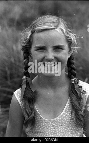 Une jeune fille avec ses cheveux tressés en smilng l'appareil photo. Banque D'Images