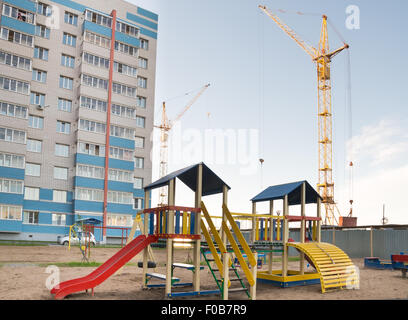 Grue de construction et une aire de jeux dans la cour Banque D'Images