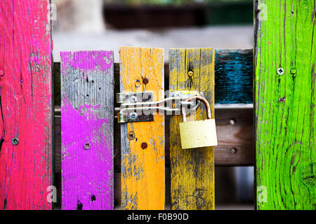 Vieille clôture en bois multicolores avec une serrure Banque D'Images