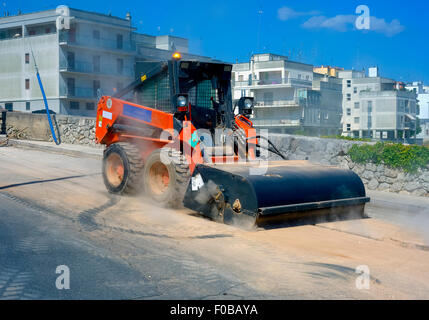 Sweeper mini pelle pièces jointes. La balayeuse balaie, recueille et déverse la saleté et les débris. Banque D'Images