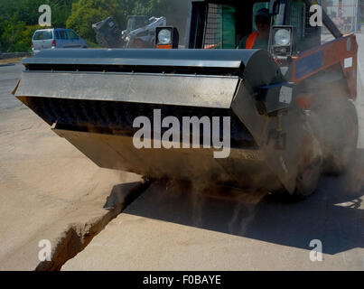 Sweeper mini pelle pièces jointes. La balayeuse balaie, recueille et déverse la saleté et les débris. Banque D'Images