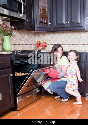 Jolie femme four d'ouverture avec un plateau de cookies Banque D'Images