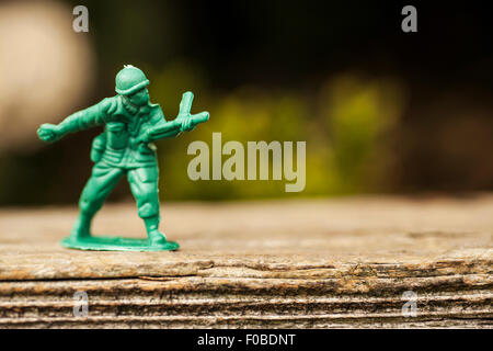 Petits soldats en plastique vert/armée de hommes en mission dans l'arrière jardin entouré de pelouse et fleurs Banque D'Images